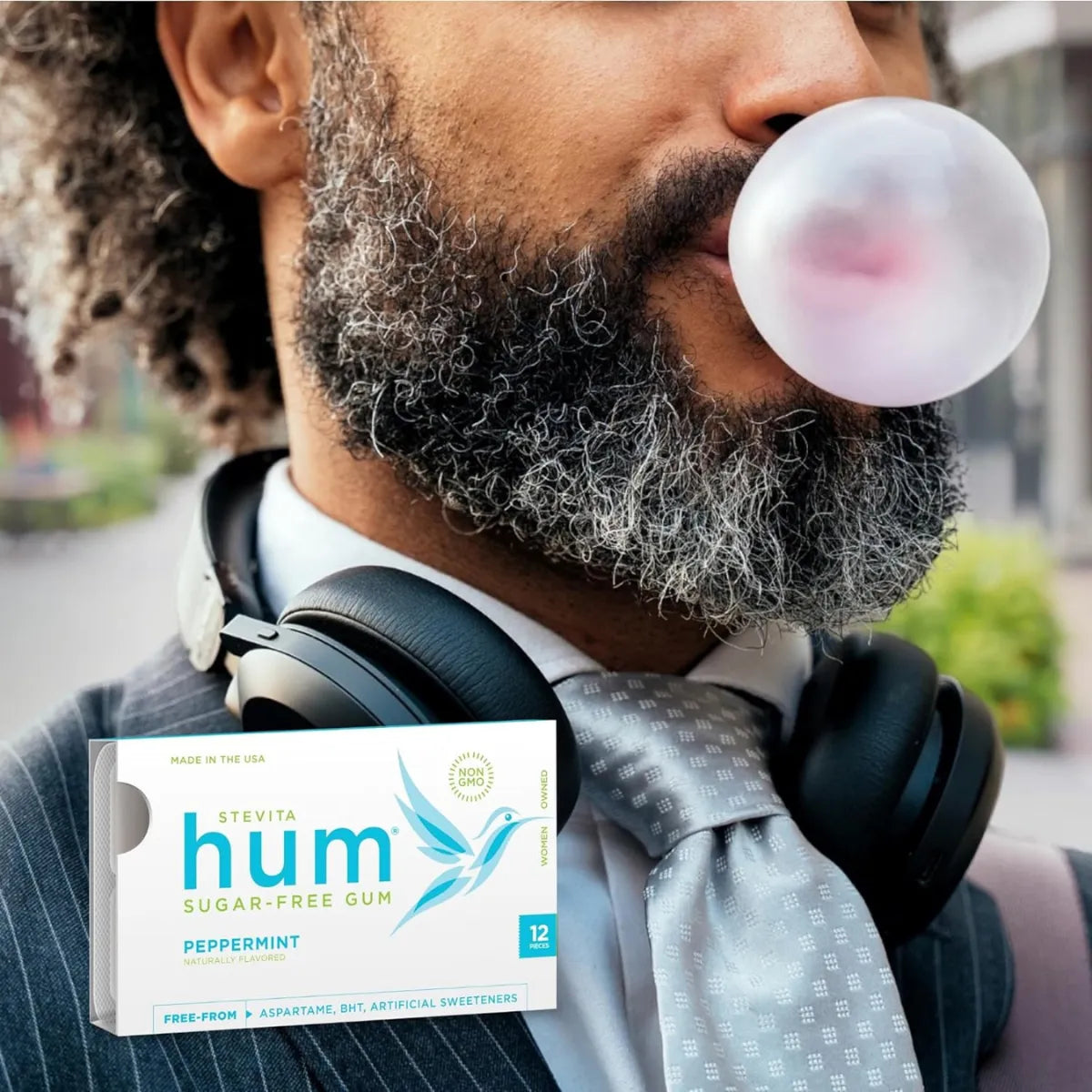 Man blowing a bubble with Stevita Hum peppermint sugar-free gum packaging