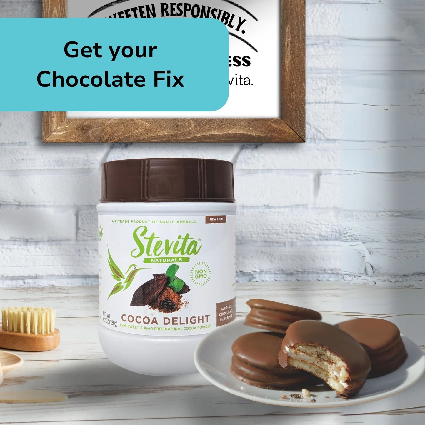 A jar of Stevita Cocoa Delight near a plate of chocolate-covered cookies. A wooden brush is nearby. Text above reads, "Get your Chocolate Fix."